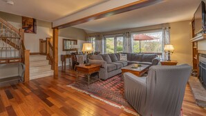 A spacious living room with a wooden staircase, a dining area, and a fireplace. - Townhome with Fireplace & Hill Views, Saltbox (Hartford)