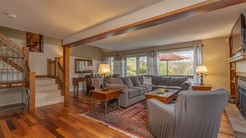 A spacious living room with a wooden staircase, a dining area, and a fireplace.
