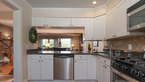 A modern kitchen with white cabinetry, a stainless steel dishwasher, a gas stove, and a view to the living area. - Townhome with Fireplace & Hill Views, Saltbox (Hartford)