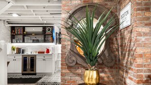 Una cocina con gabinetes blancos, salpicadero y pared de ladrillo. Hay un letrero que dice "BOSTON CITY LIMITS".