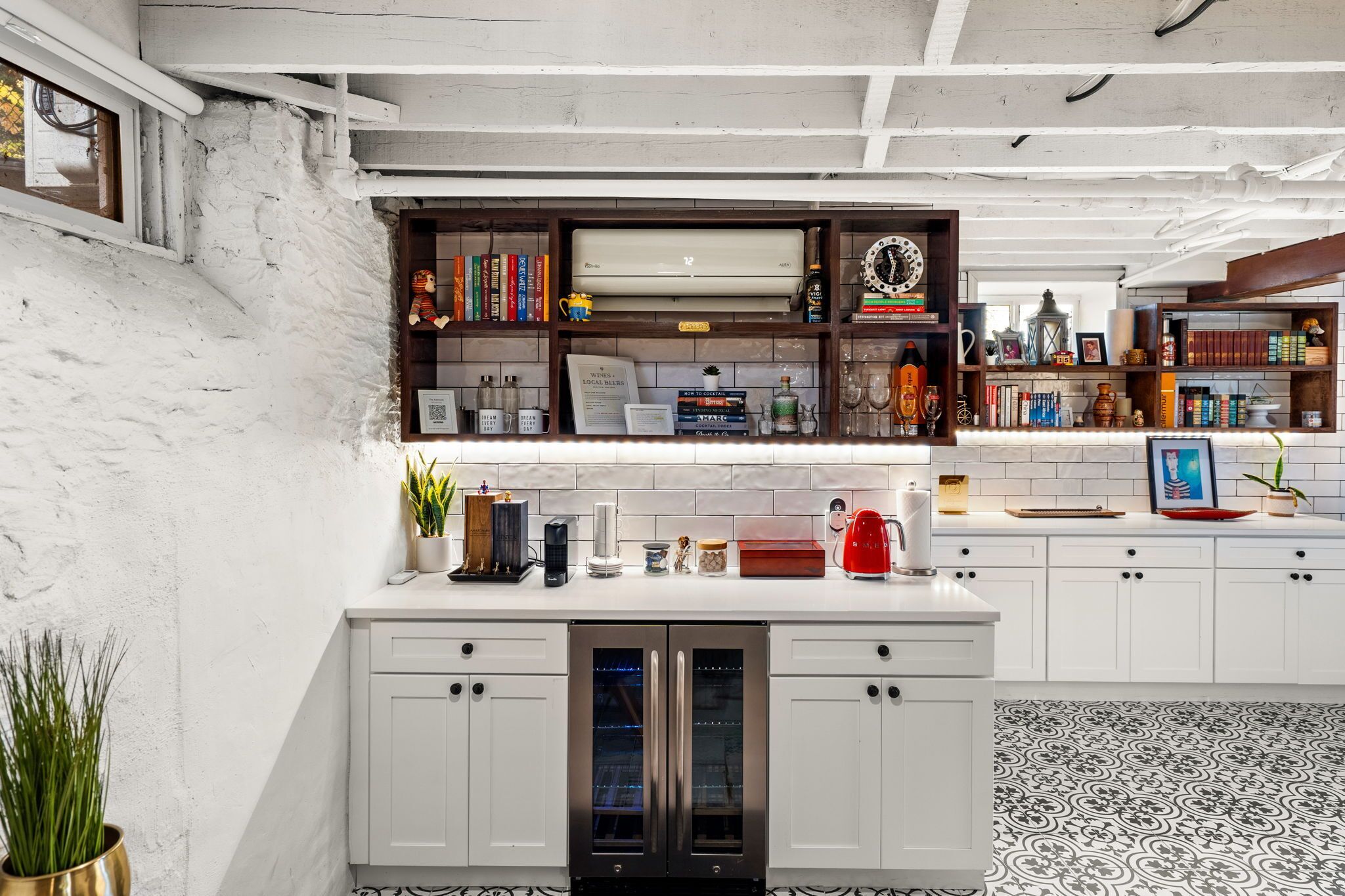 Een moderne keuken met witte keukenkastjes, een inbouwoven en diverse keukenapparaten en decoratieve accessoires.