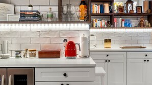 Una cocina moderna con armarios blancos, una tetera roja y varios utensilios de cocina sobre la encimera.