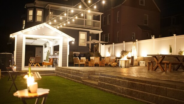 Un patio exterior con zona de estar cubierta, una chimenea y un ambiente agradable e iluminado.