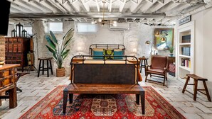 Un dormitorio rústico con vigas a la vista, una cama, una estantería y una planta grande.