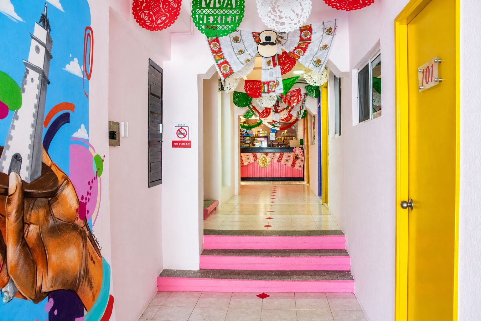A hotel hallway with a staircase leading to a reception area, decorated with festive items and a 'NO SMOKING' sign.