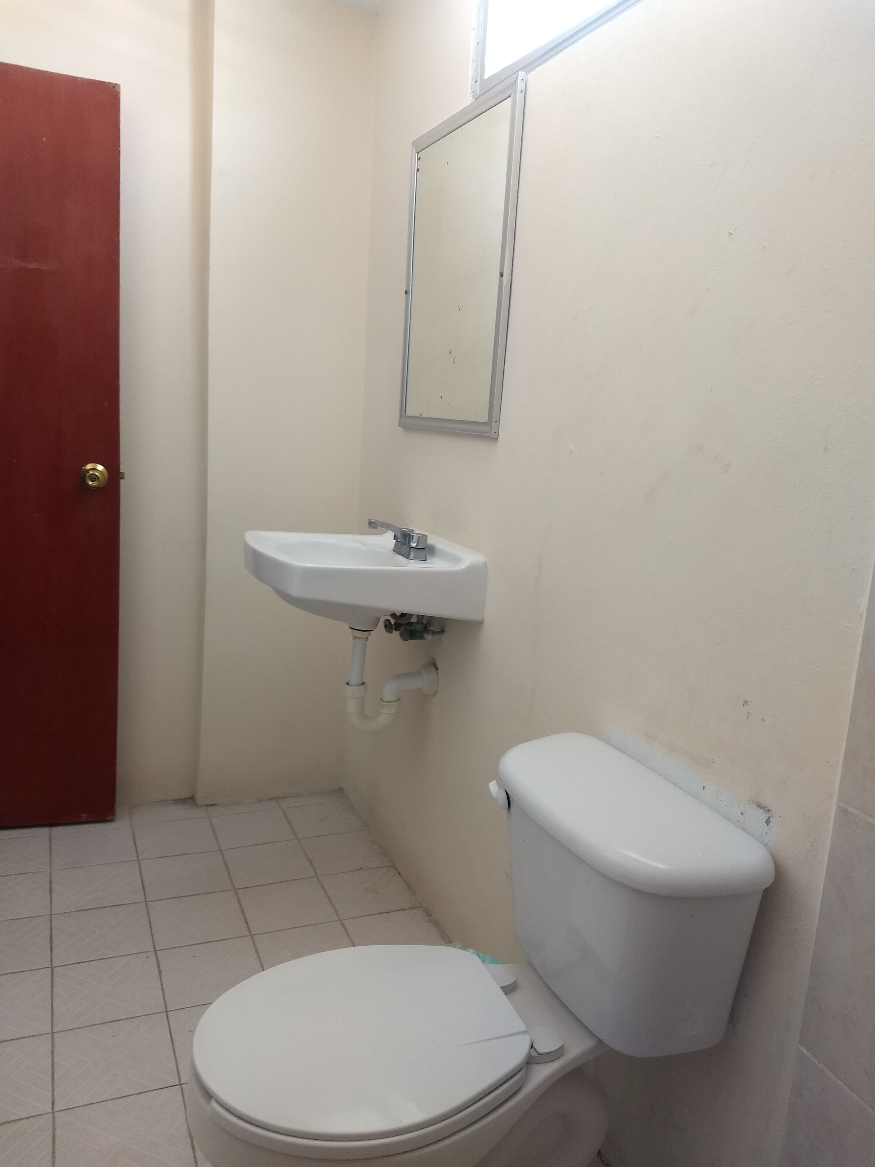 Ein kleines Badezimmer mit Toilette, Waschbecken und einer roten Tür.