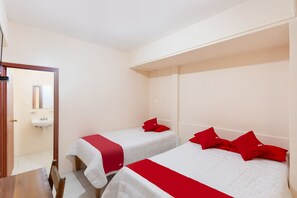 A hotel room with two beds, each with a red pillow and white bedding. A wooden table and chair are visible in the foreground. - Rosa del Alba, Barrio Mágico Centro Histórico de Chetumal (Chetumal)