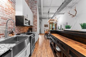 Une cuisine moderne avec un mur en briques, des appareils en acier inoxydable et un coin repas en bois.