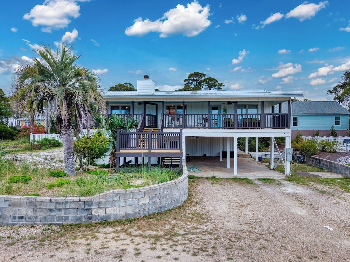 A two-story house with a balcony, a covered porch, and a gravel driveway.