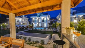 A modern outdoor patio area with a pool, lounge chairs, and a bar with drinks. - 4 bedroom luxury villa sardunya B in oludeniz fethiye (Fethiye)