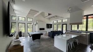 A modern kitchen with a central island, dining table, and seating area. - Modern Nordic Villa 3 miles from Beaver Stadium (State College)