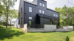 A modern two-story house with a dark exterior, a front porch, and a well-maintained lawn. - Modern Nordic Villa 3 miles from Beaver Stadium (State College)