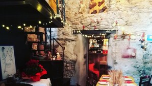 A dining area with a long table set for a meal, stone walls, and a staircase leading to an upper level. - Il Mondo In Valle (Pessinetto)