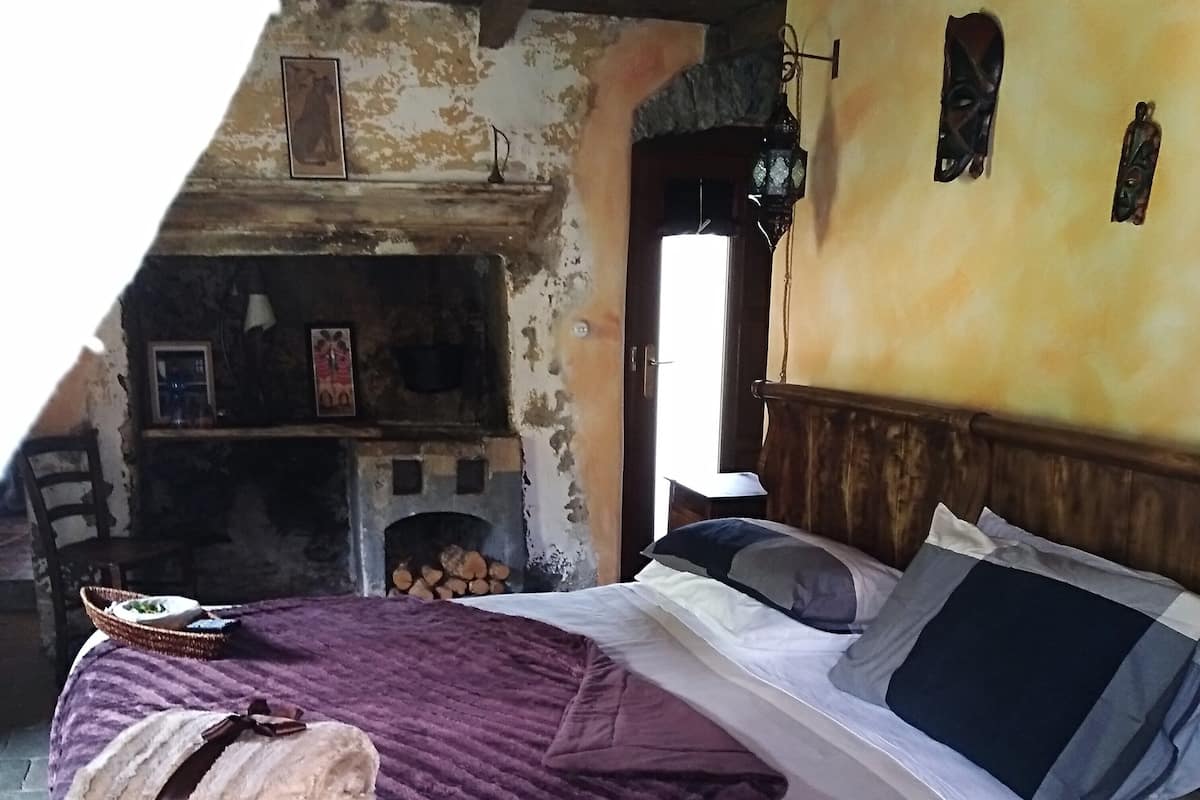A bedroom with a bed, a fireplace, a rustic wall, and a wooden headboard.