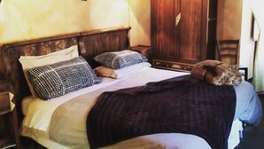 A bed with a wooden headboard, two bedside tables, a nightstand, a wall-mounted light fixture, and a wardrobe. - Il Mondo In Valle (Pessinetto)