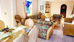 Un salón con una mesa de centro de cristal, sofás con estampado floral y una mesa de comedor con frutero.