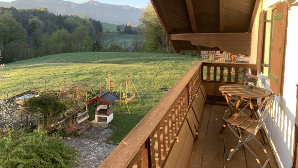 A wooden balcony with a view of a grassy field and mountains. - Vacation in the countryside with mountain views and close to the Chiemsee (Frasdorf)