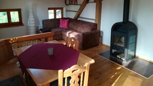 A cozy living room with a wooden floor, a brown sofa, a table with a purple tablecloth, a fireplace, and a skylight. - Vacation in the countryside with mountain views and close to the Chiemsee (Frasdorf)