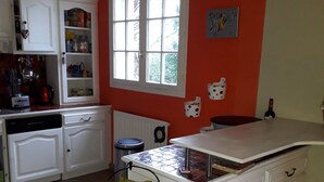 Eine Küche mit weißen Schränken, einem Obstkorb und einem Fenster.