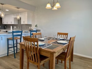 A dining area with a wooden table set for four, surrounded by wooden chairs.