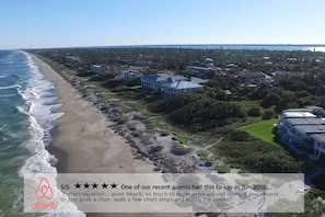 Luftaufnahme einer Küstenlandschaft mit Strand, Häusern und einem großen Gebäude.