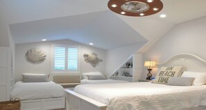A modern bedroom with two beds, a ceiling fan, and decorative shells on the walls.