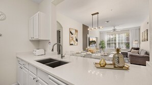 A modern kitchen with a large island, white cabinetry, and a dining area with a sofa and coffee table.