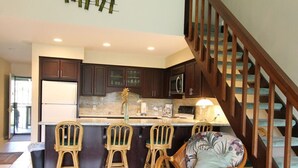 A modern kitchen with dark wooden cabinets, a marble countertop, and a central island with bar stools. - SeaHorseShort Term on Golf Course, Upper Floor - Have a relaxing vacation (Kahuku)