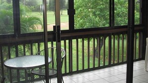 A covered outdoor area with a glass door, a metal table, and chairs. - SeaHorseShort Term on Golf Course, Upper Floor - Have a relaxing vacation (Kahuku)