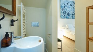 Ein Badezimmer mit einem großen weißen Waschbecken, einem Handtuchhalter, einem Händetrockner und einem an der Wand montierten Lichtschalter.