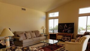 A living room with a sofa, armchairs, a coffee table, and a television. - Unobstructed mountain views (Tucson)