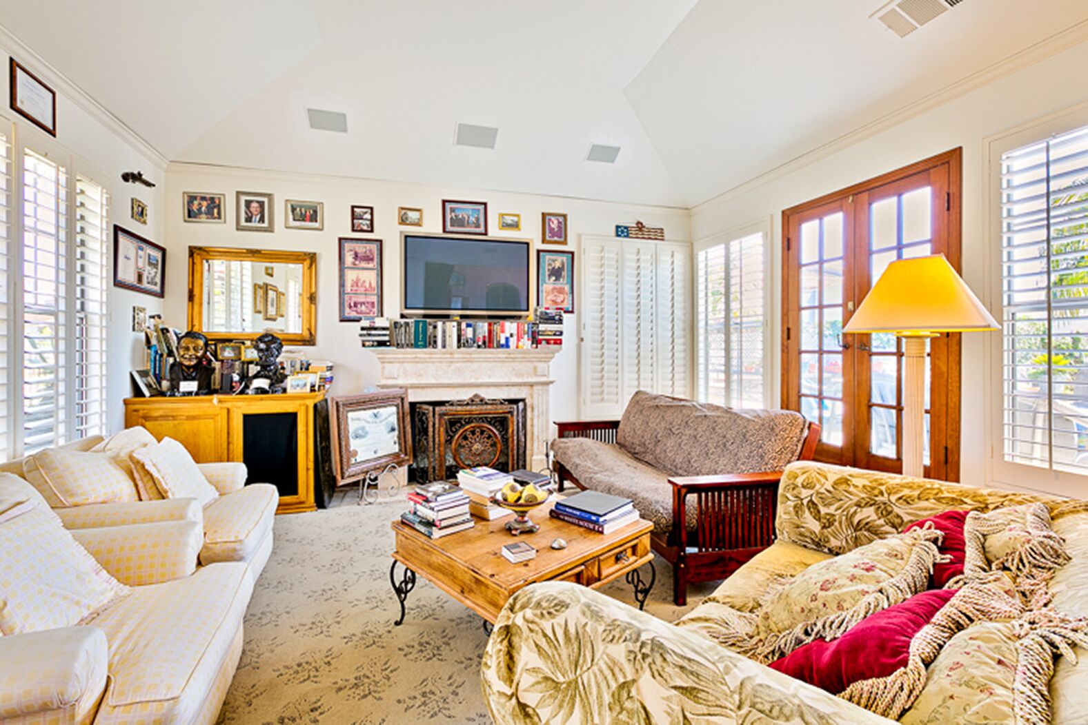 A living room with a fireplace, a television, and various framed pictures on the wall.