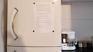 A kitchen with a white refrigerator, a white microwave on top, and a coffee maker on the counter.