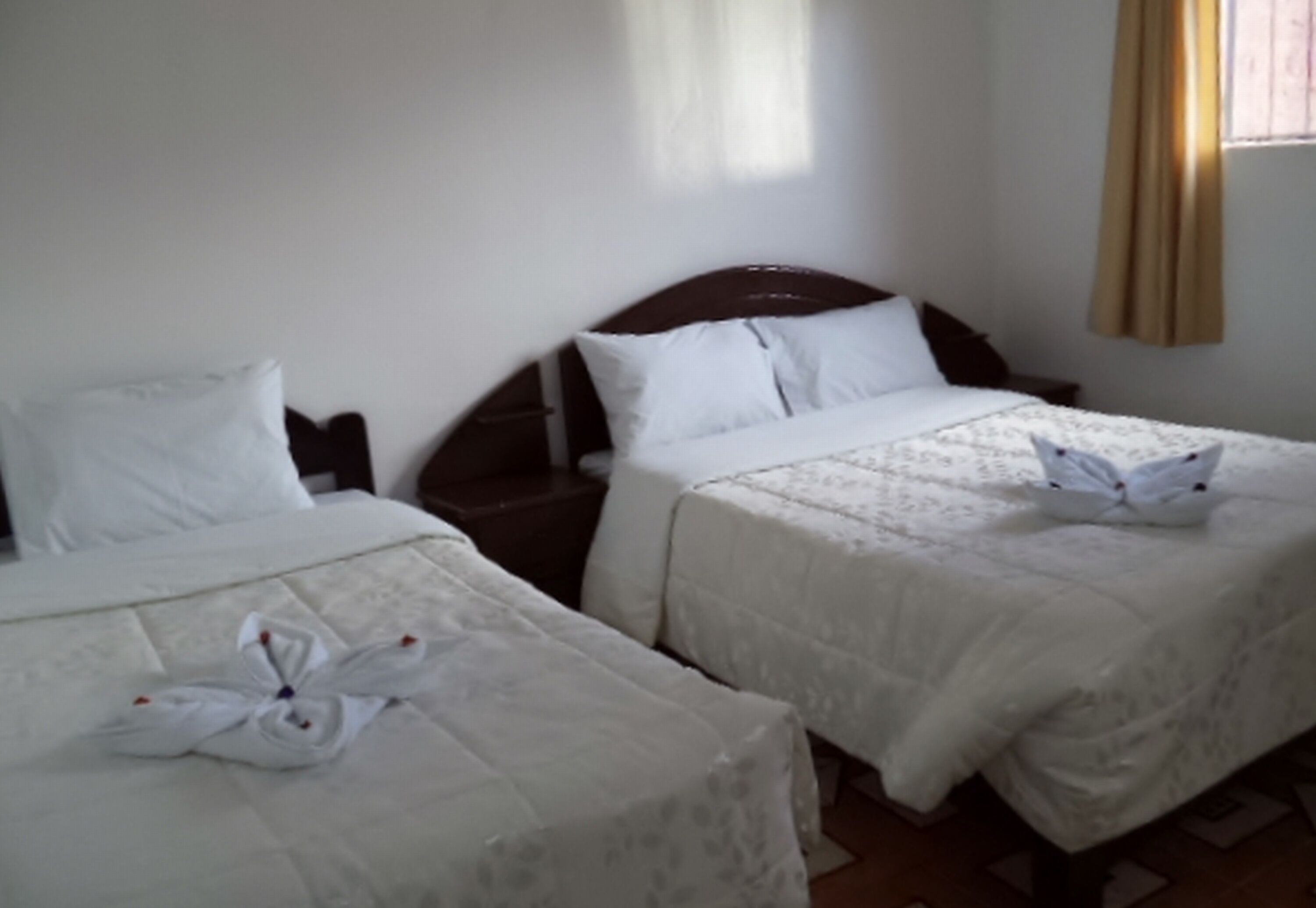 Ett hotellrum med två sängar, båda med vita sängkläder och ett blommönster.