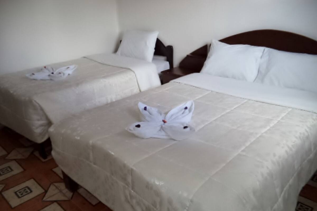 Two twin beds with white linens and a decorative towel arrangement on the headboard.