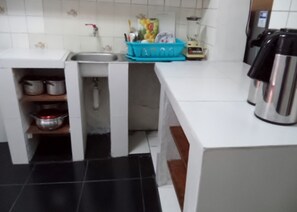 Una cuina compacta amb un rentapeus, un escorredís blau i una cafetera.