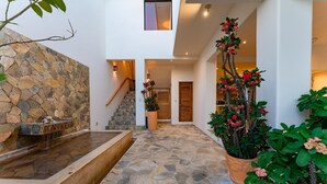 A stone-floored courtyard with a water feature, potted plants, and a staircase leading to an upper level. - Vista Hermosa (Santa María Huatulco)