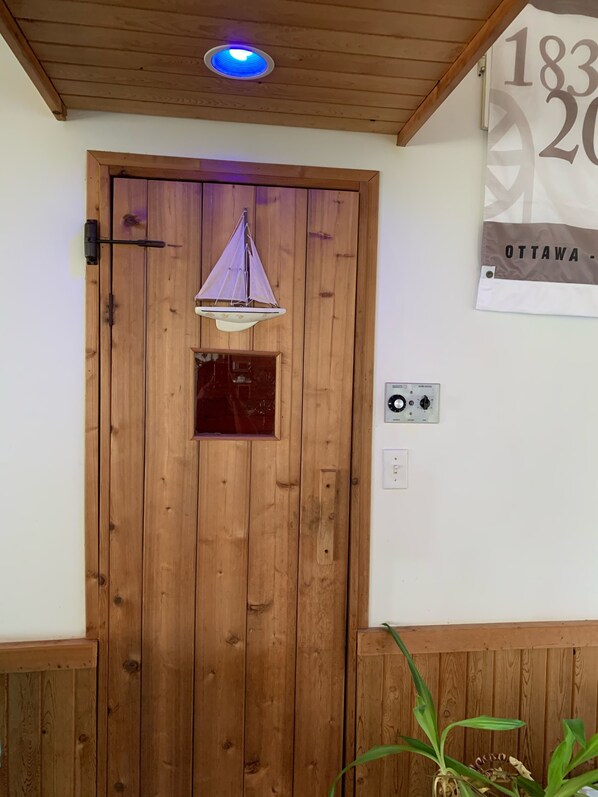 A wooden door with a small window, a hanging light fixture, and a wall-mounted thermostat. - All Year Lakefront Getaway in a private guest rm & indoor heated pool !! (Westport)