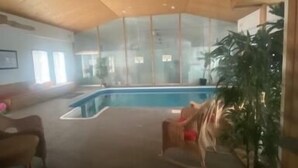 A spacious indoor area with a wooden ceiling, a large window, and a pool. - All Year Lakefront Getaway in a private guest rm & indoor heated pool !! (Westport)