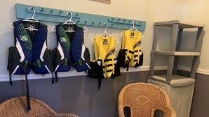A room with a wall-mounted rack holding several sports jerseys, two wicker chairs, and a small shelving unit. - All Year Lakefront Getaway in a private guest rm & indoor heated pool !! (Westport)