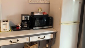 A kitchenette with a microwave, toaster, and coffee maker on a white countertop. A white refrigerator is to the right. - All Year Lakefront Getaway in a private guest rm & indoor heated pool !! (Westport)