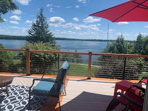 Une terrasse avec vue sur un lac, un parasol rouge et du mobilier d’extérieur.