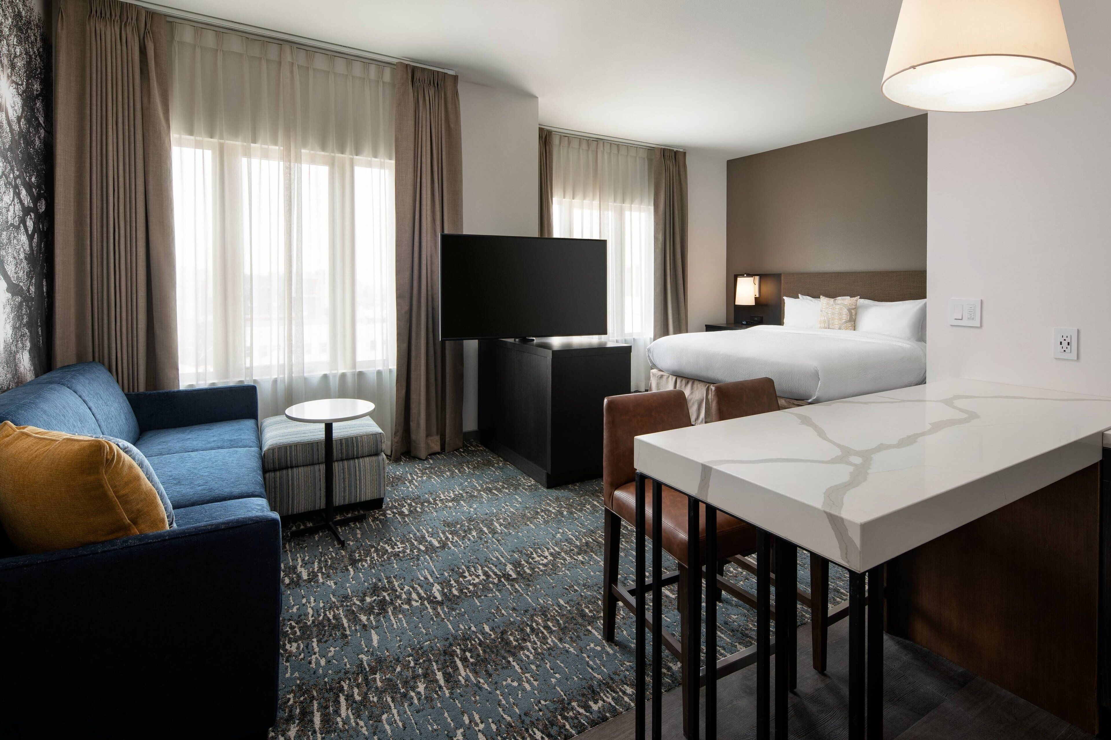 Une chambre d’hôtel équipée d’un lit, d’une télévision, d’un canapé, d’une petite table et d’un bureau.