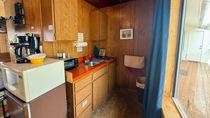 A compact kitchen with wooden cabinets, a coffee maker, a microwave, and a sink.