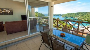 Ein Balkon mit Glastisch und Stühlen, einer Couch und einem Bild an der Wand.