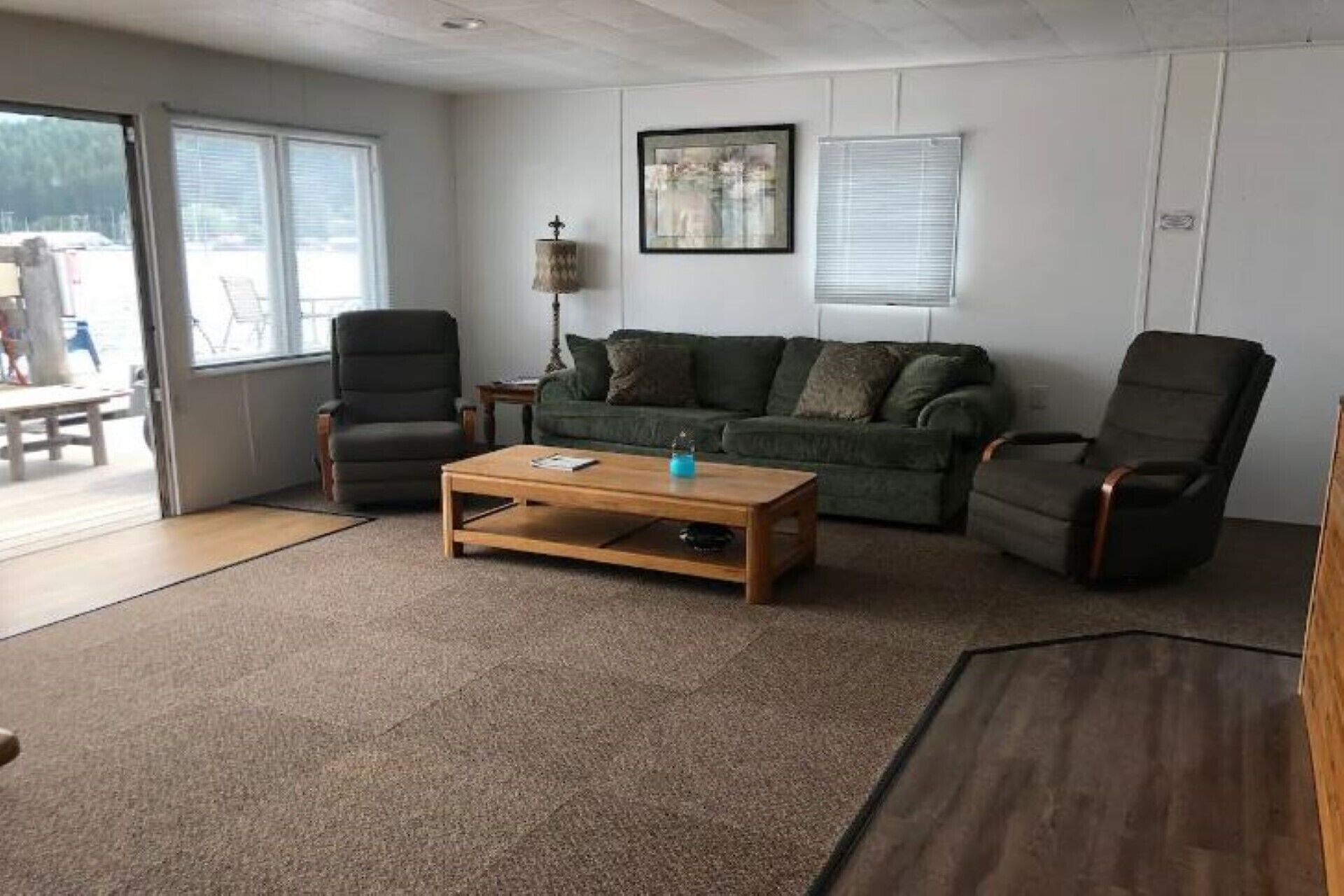 Ein Wohnzimmer mit einer Couch, zwei Sesseln, einem Couchtisch und einer Stehlampe.