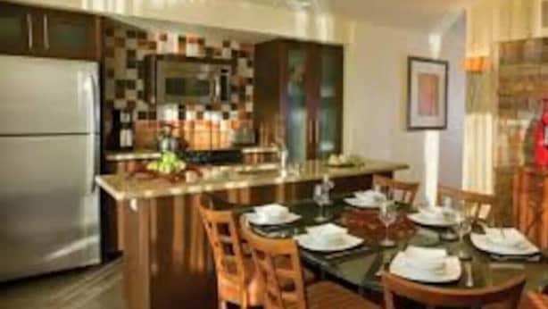 A modern kitchen with a central island, wooden chairs, and a dining table set for four.