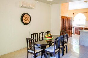 A dining area with a round table, six chairs, and a decorative wall hanging. - Hacienda Real (Santa María Huatulco)