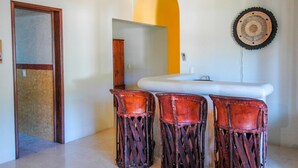 Une salle de bain avec un lavabo blanc, un miroir et trois tabourets en bois.