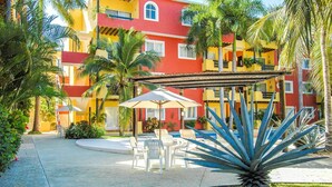 Une cour avec une piscine, des espaces de détente en plein air et des palmiers.